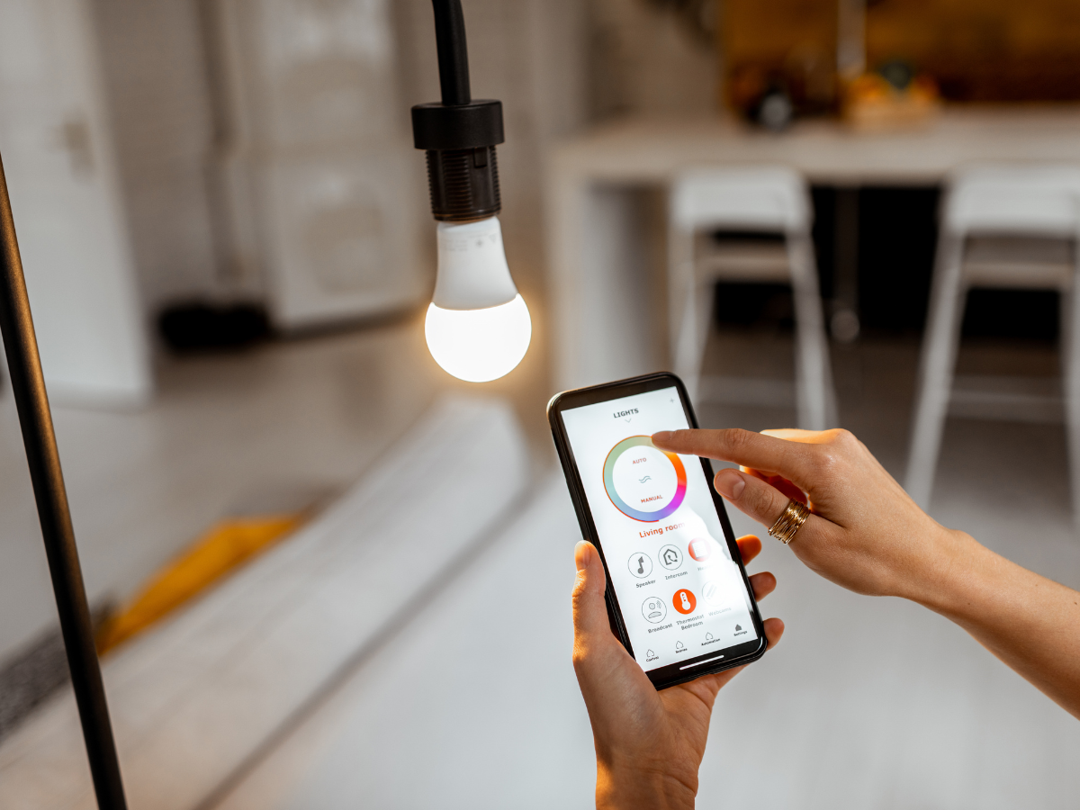 Effective Lighting Design for Home Remodeling 4 A person uses a smartphone app to control a smart light bulb, showcasing innovative lighting design in a modern, bright room.