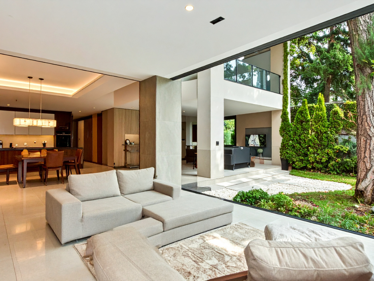 Achieving a Minimalist Design in Your Home Remodel 2 Modern open-plan living room with beige sectional sofa, large sliding glass doors, and a view of a landscaped patio and garden area, all enhanced by a minimalist design that emphasizes clean lines and natural light.