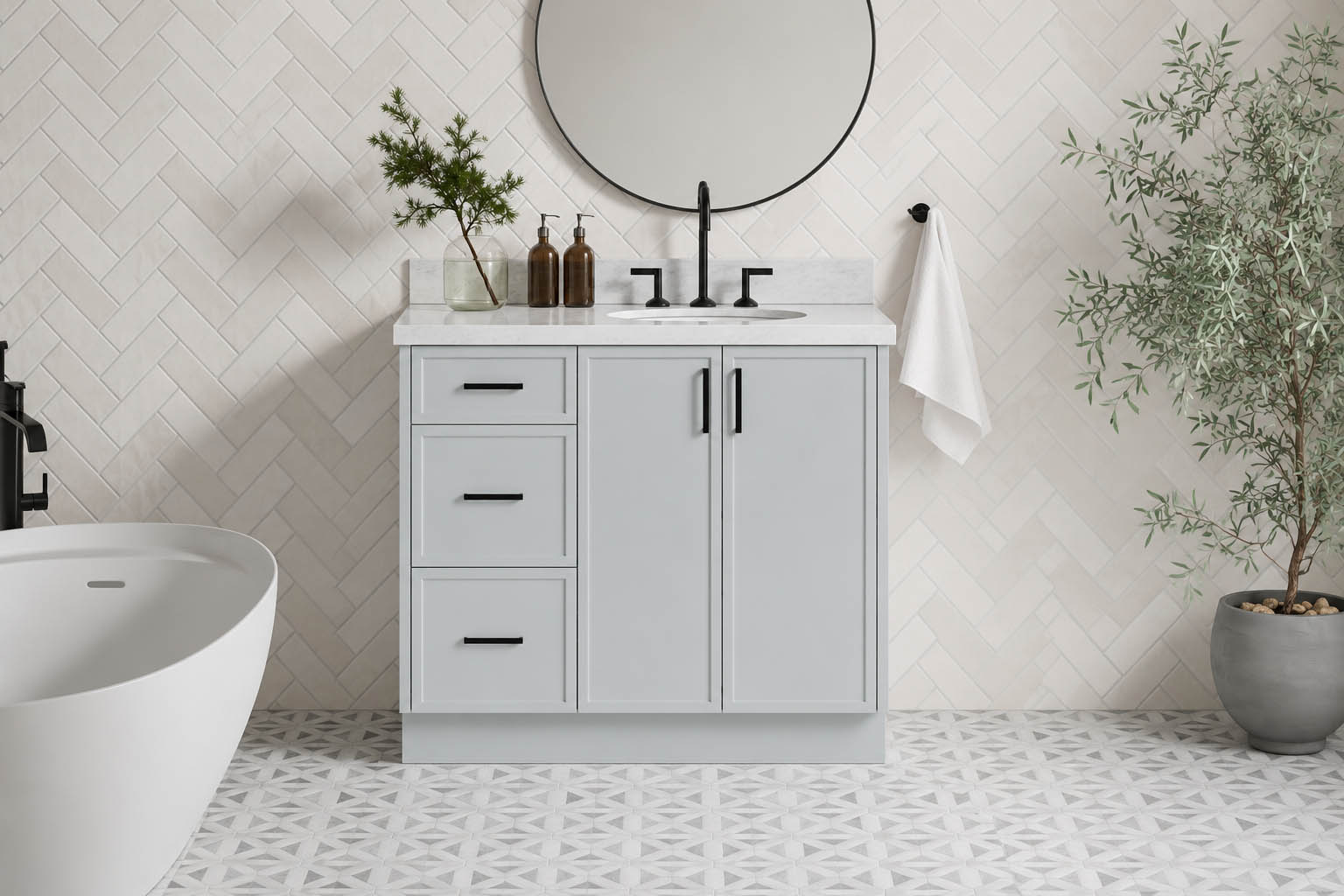 Modern bathroom with a gray vanity, round mirror, black fixtures, potted plants, towel on a hook, and geometric patterned floor tiles—an inspiring office restroom transformation featuring ARIEL bathroom vanities and storage.