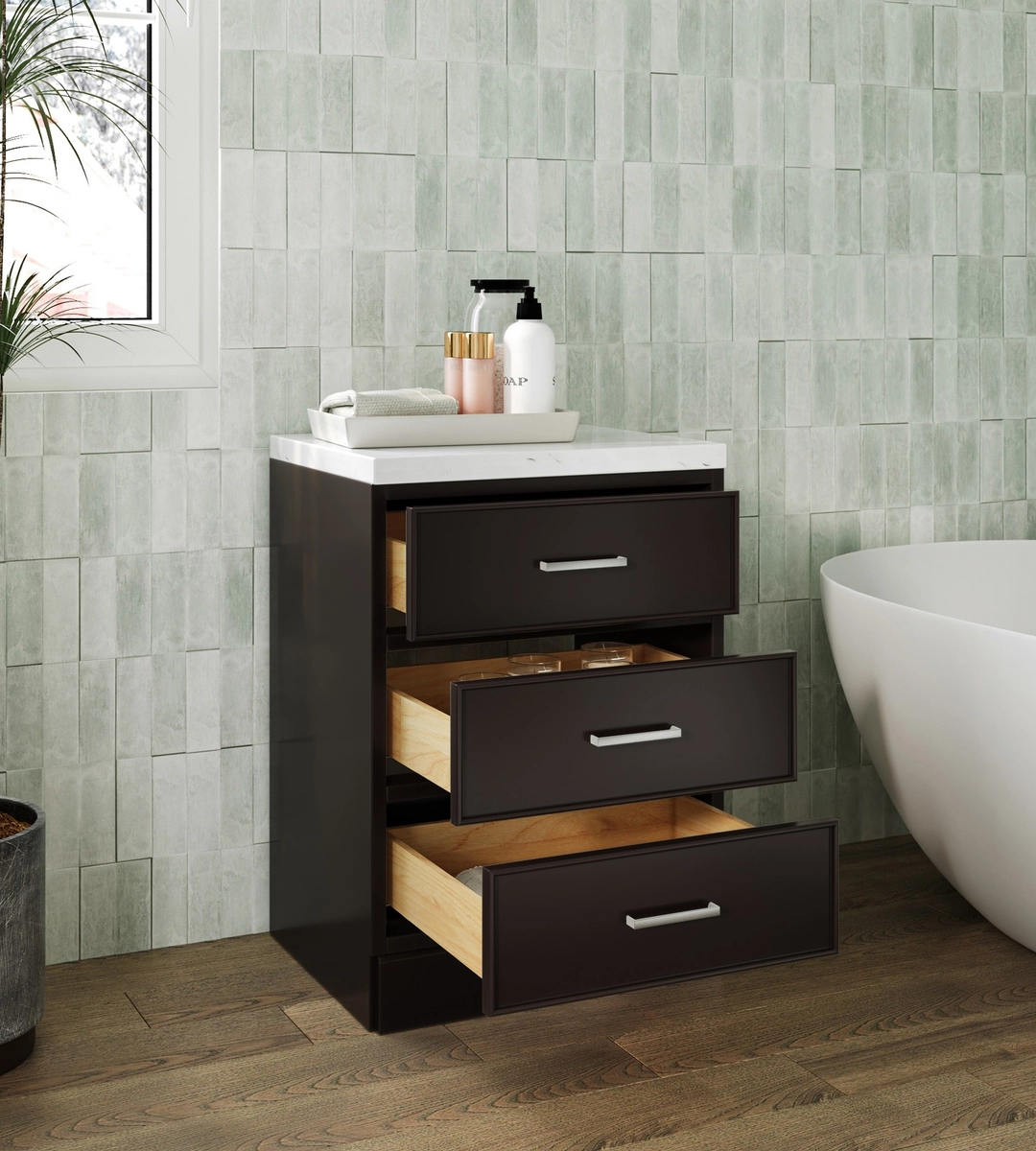 A bathroom vanity with an open sink, soap dispenser, folded towels, and three drawers partially open, set against a tiled wall and wooden floor—perfect for any office restroom transformation using ARIEL bathroom vanities and storage.