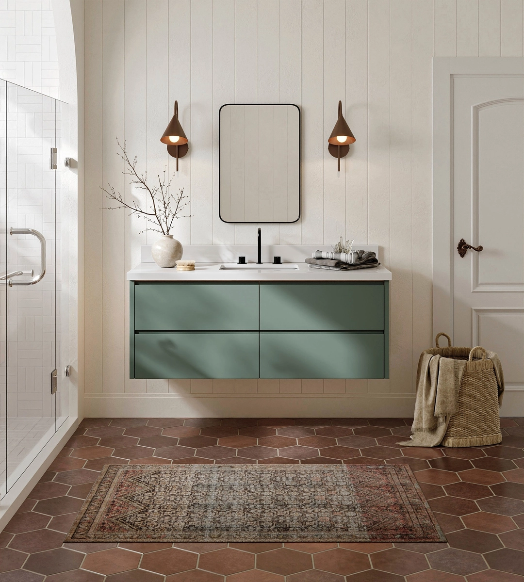 Modern bathroom with a floating green vanity—perfect for a business restroom upgrade—rectangular mirror, two wall sconces, and a patterned rug on a hexagonal tile floor. This space exemplifies contemporary commercial restroom design while featuring stylish ARIEL bathroom vanities and storage solutions.