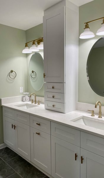 A bathroom with two sinks and a round mirror.