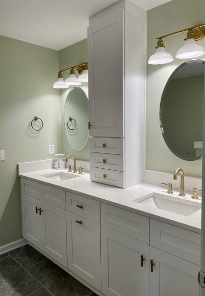 A bathroom with two sinks and a round mirror.