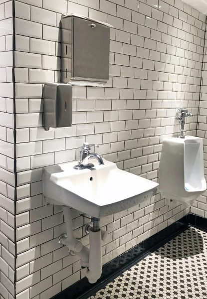 A commercial bathroom with a sink and urinal undergoing commercial remodeling services.