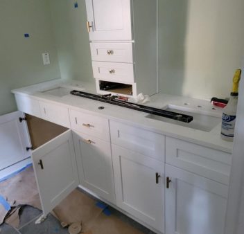 A home bathroom is being remodeled with white cabinets.