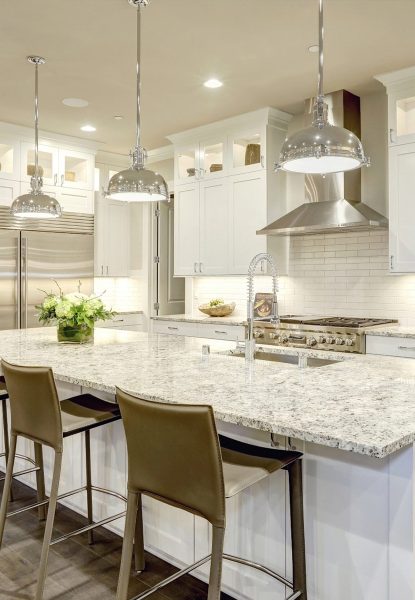 A white kitchen with granite counter tops and stainless steel appliances in a cozy home.