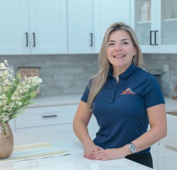 A woman in a blue shirt standing in a kitchen.