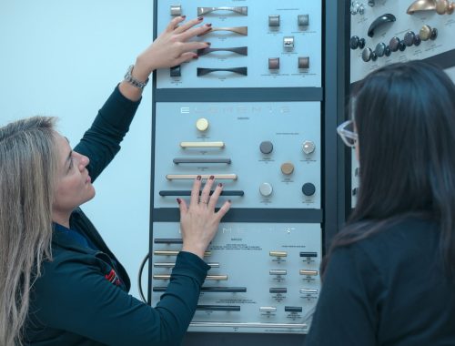 Two women looking at a display of buttons.