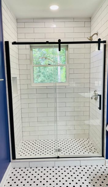 A blue and white home bathroom with a glass shower door.